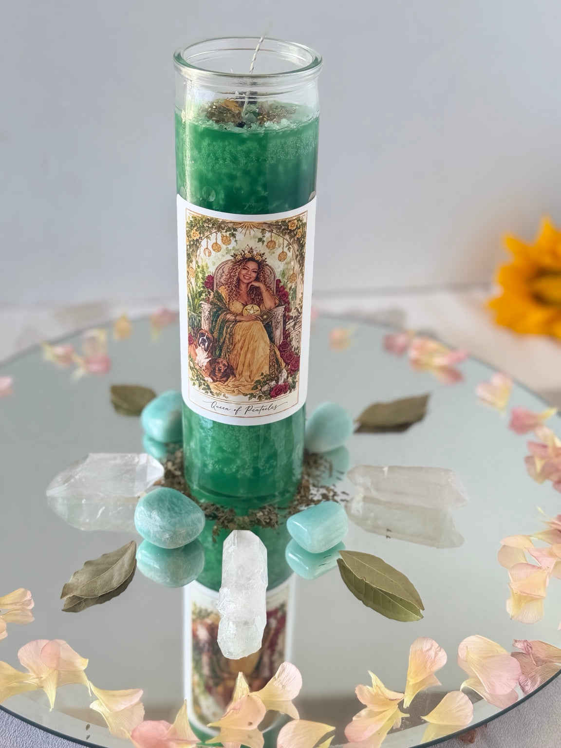 Personalized Queen of Pentacles ritual candle arranged with crystals and herbs