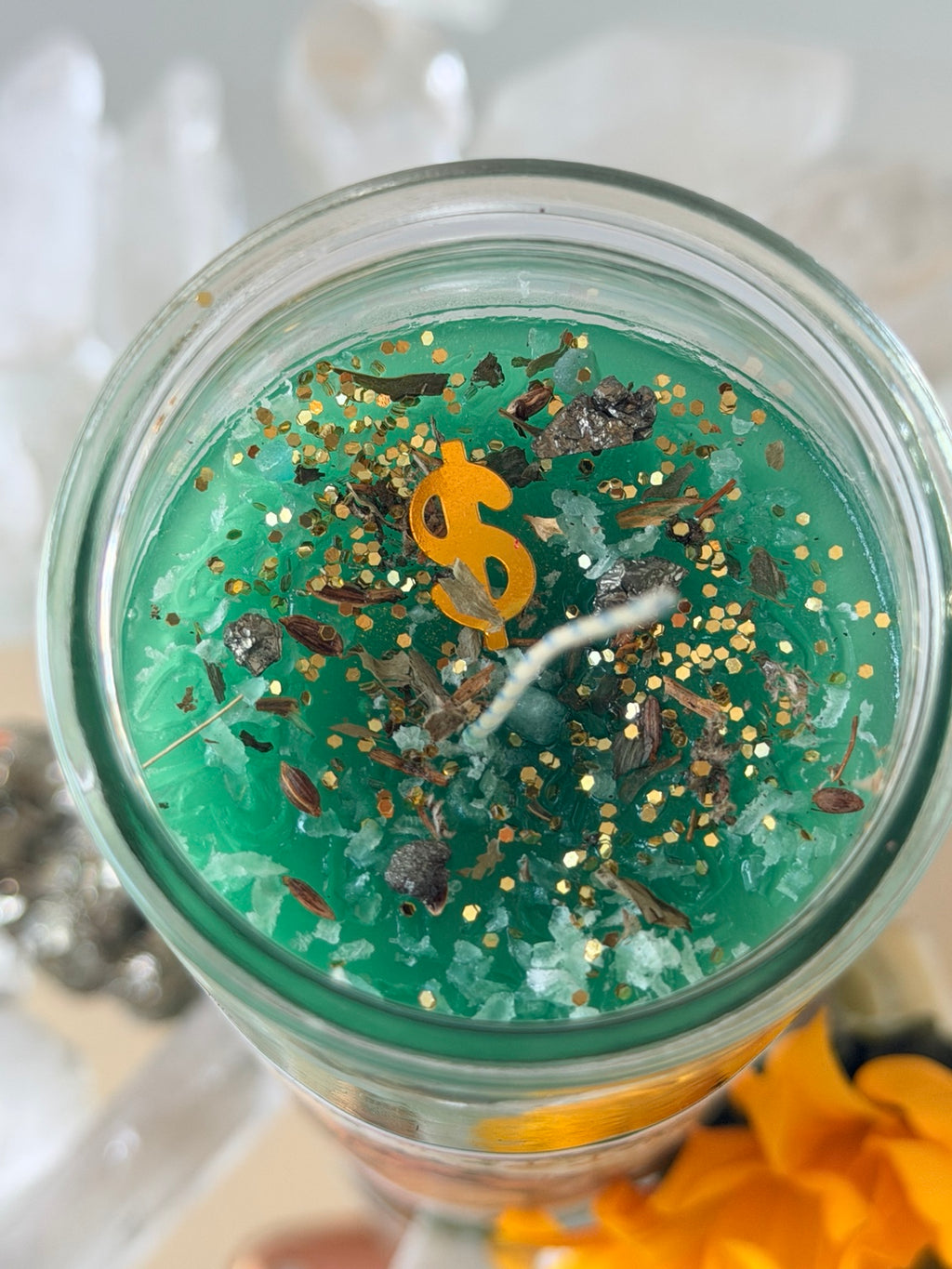 Top detail of dressed green ritual candle with herbs glitter and prosperity symbol