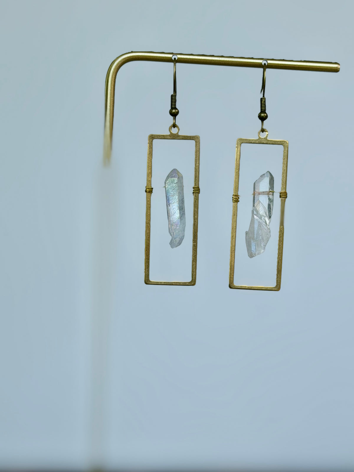 Celestial Window Angel Aura Earrings displayed on a gold jewelry stand