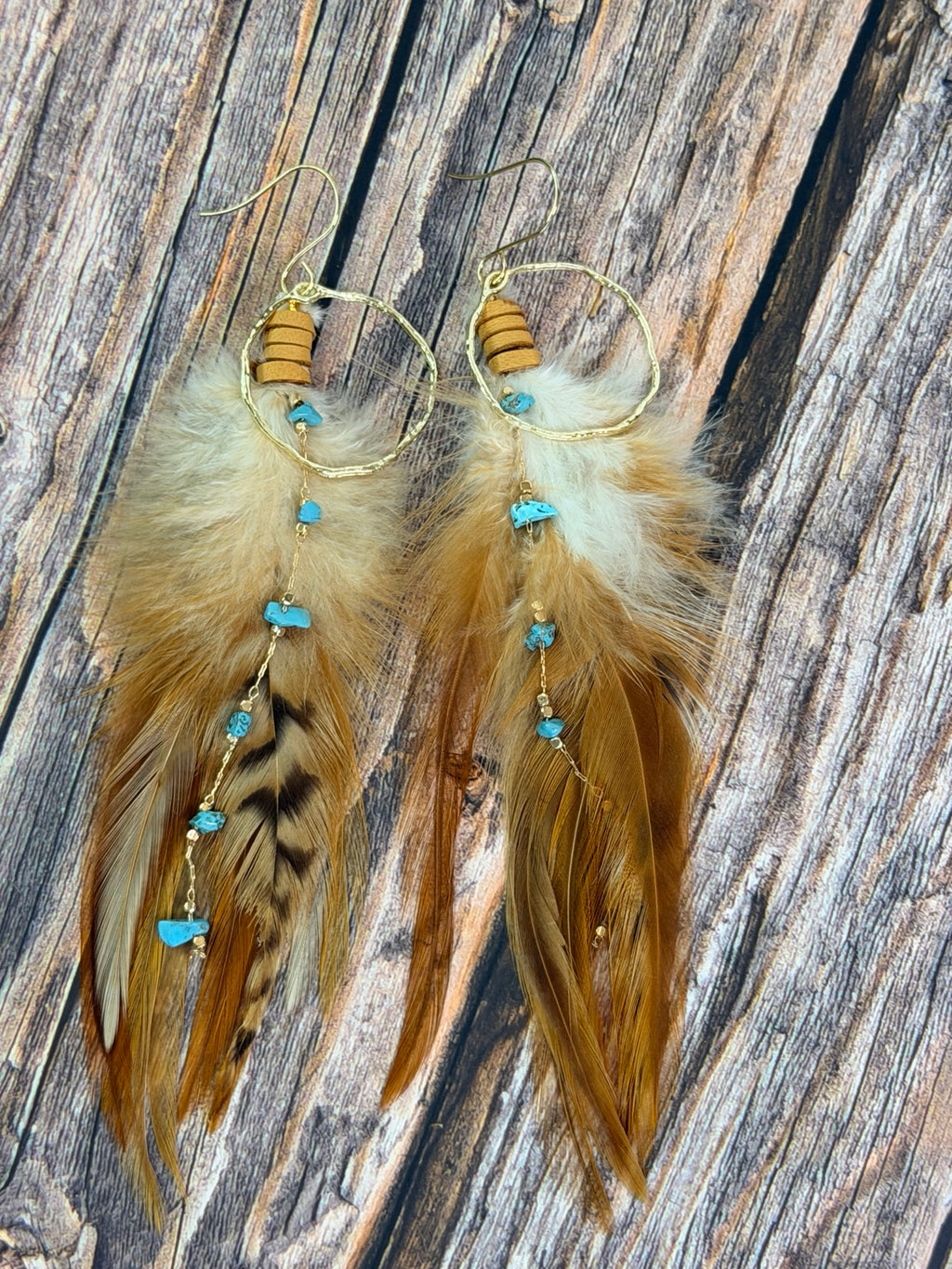 Close detail of layered brown cream and turquoise-colored feather earrings