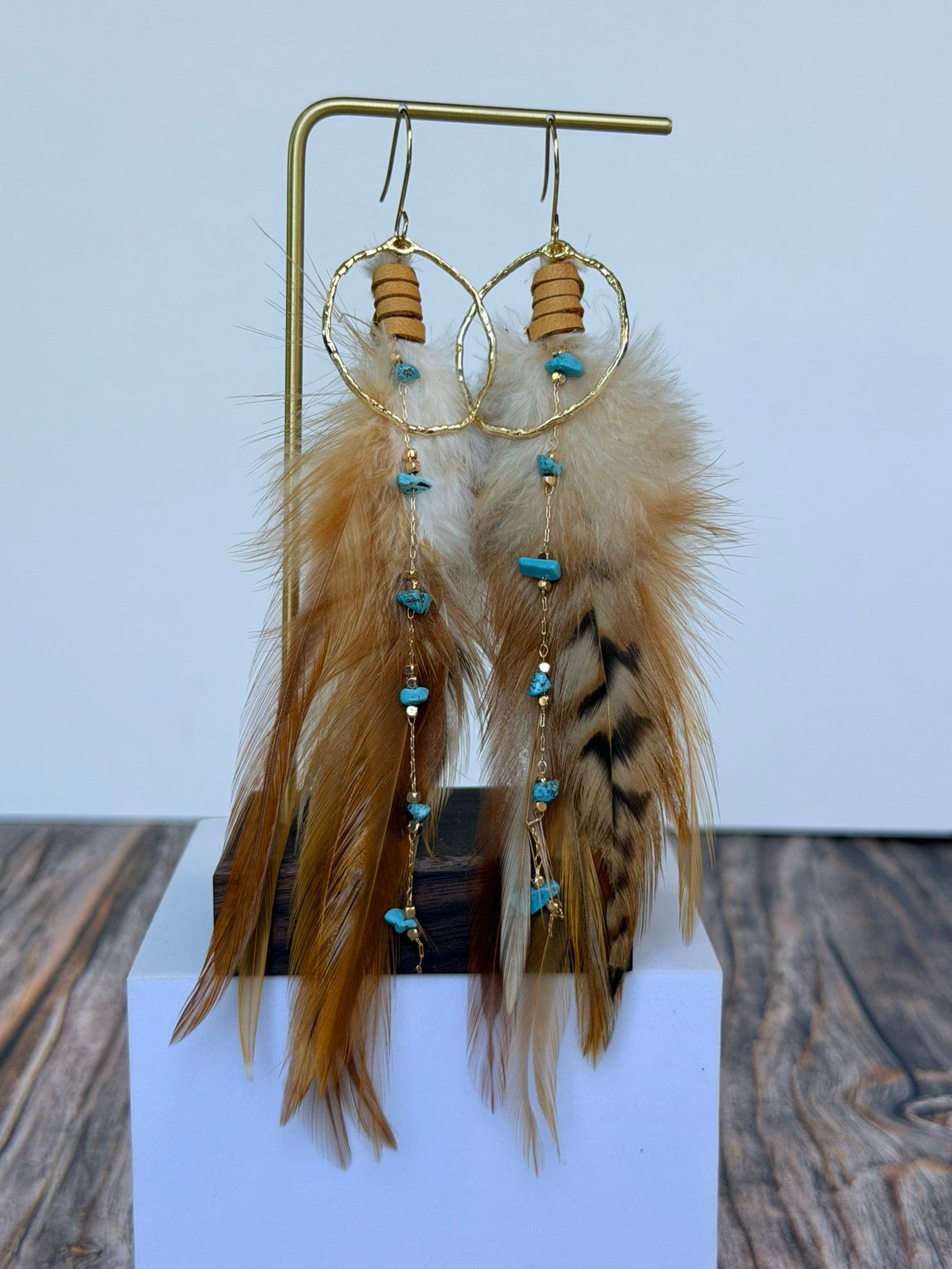 Desert Sky Feather Hoop Earrings displayed on a gold jewelry stand