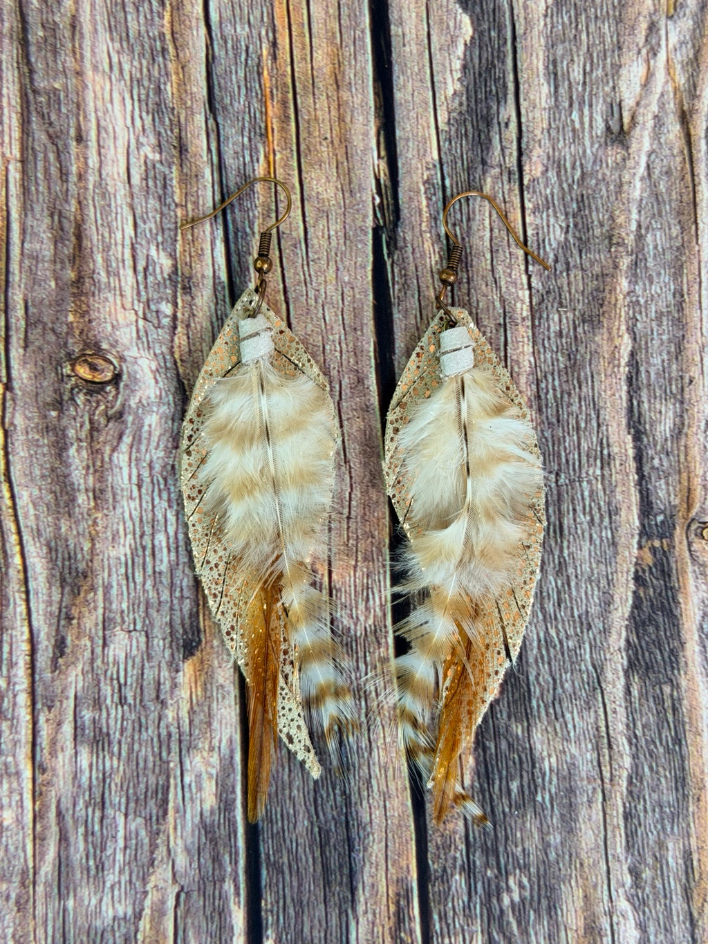 Pair of Golden Whisper Feather Earrings on a rustic wood background