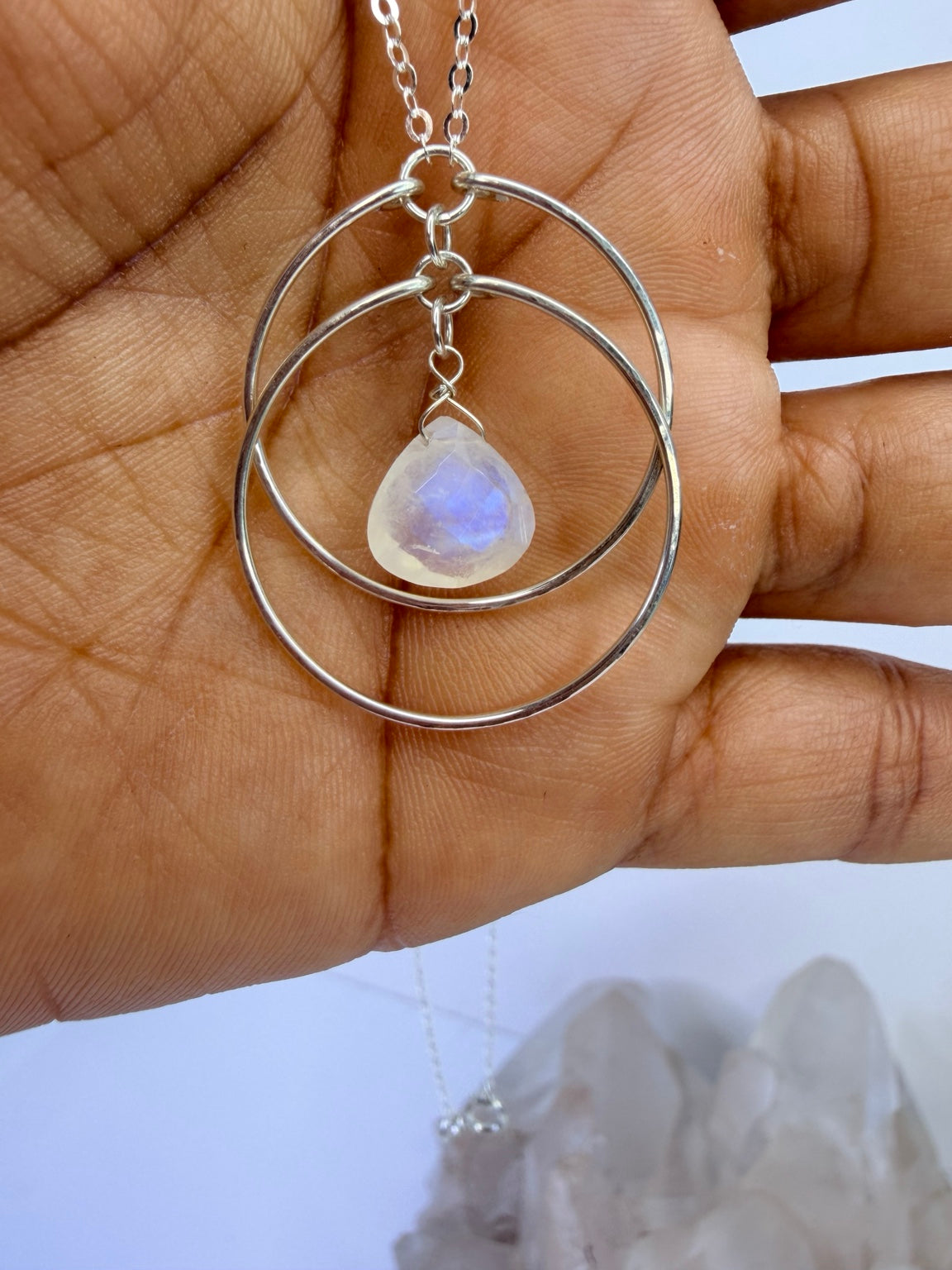 Hand-held close-up of the sterling silver moonstone circle pendant