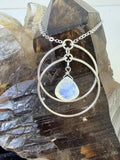 Lunar Orbit Rainbow Moonstone Necklace displayed on a natural crystal