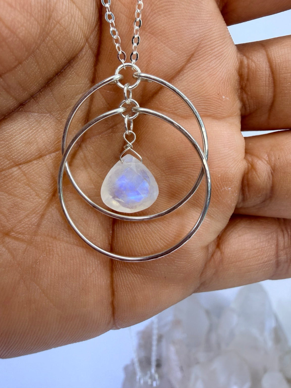 Rainbow moonstone circle necklace shown in hand for scale