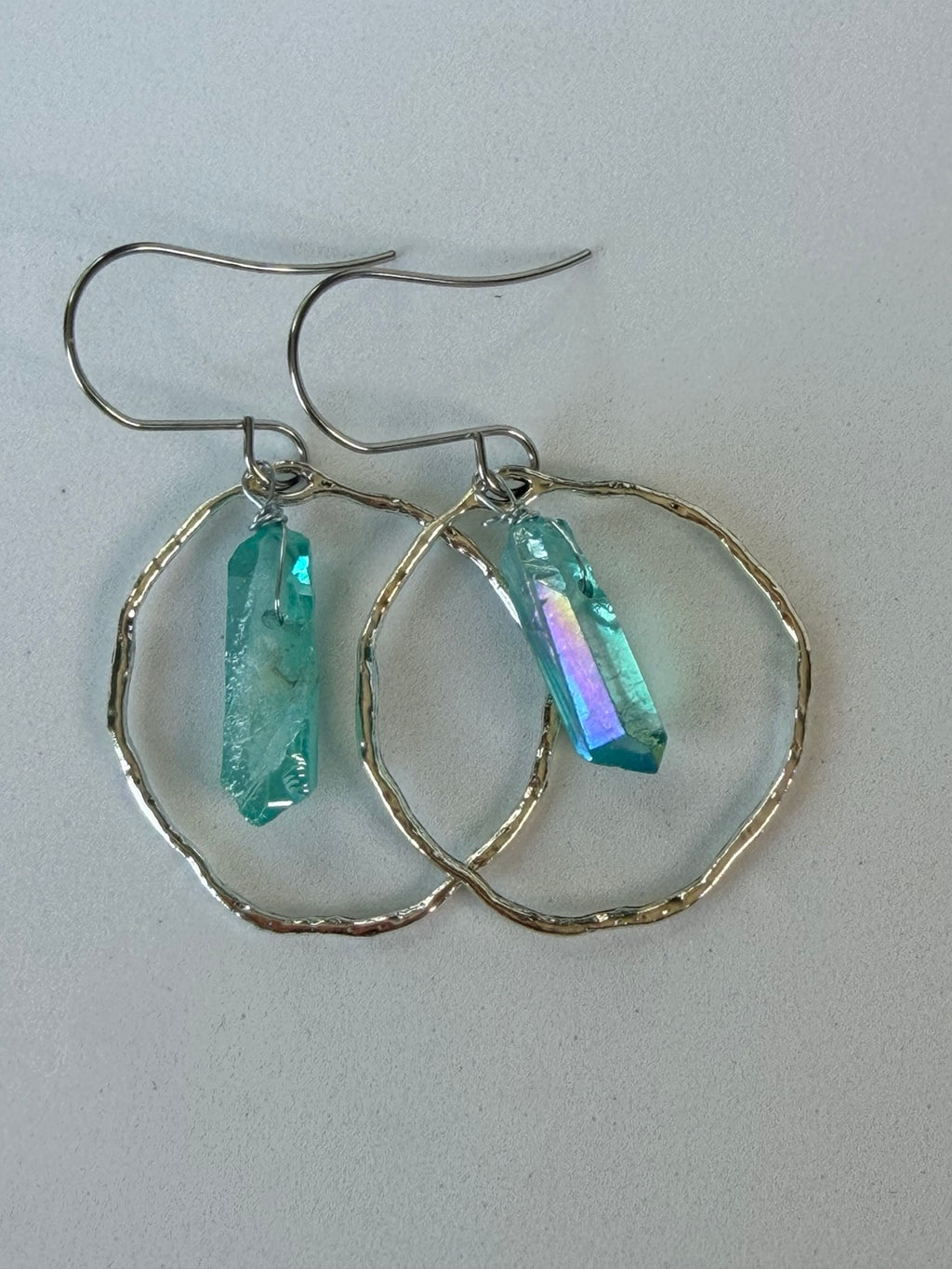 Close view of hammered silver-tone hoops with blue aura crystal points