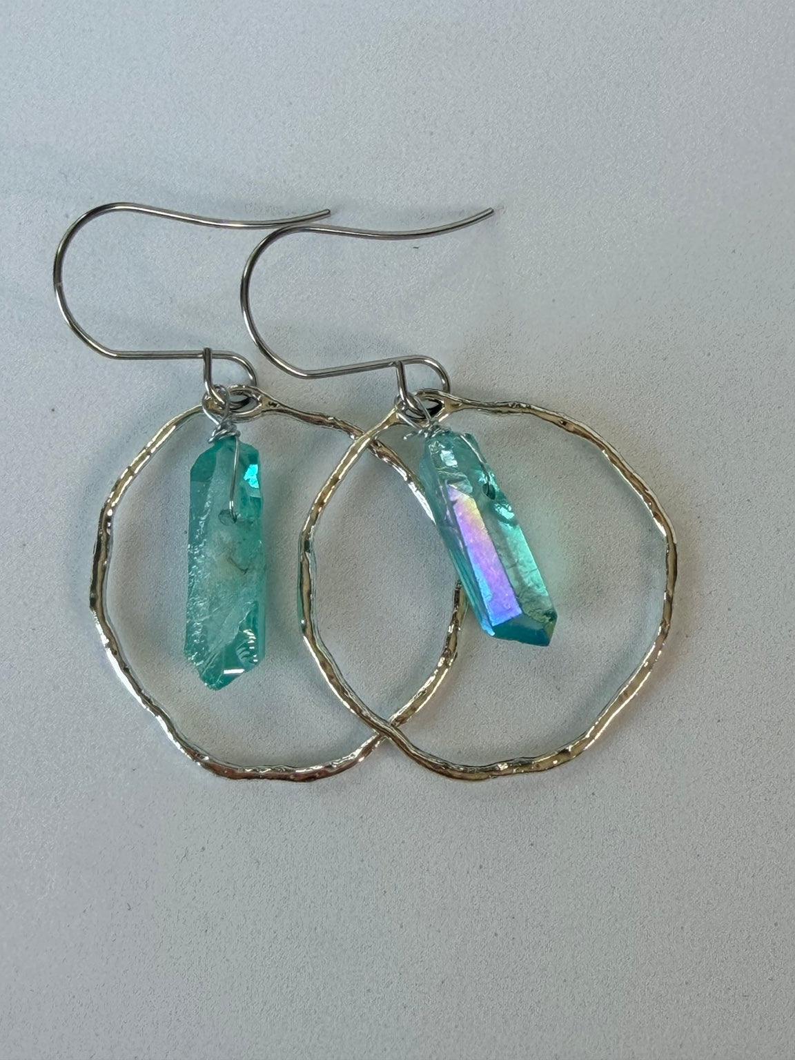 Close view of hammered silver-tone hoops with blue aura crystal points