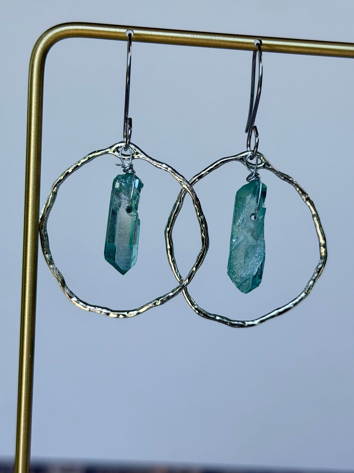 Ocean Aura Crystal Hoop Earrings displayed on a gold jewelry stand