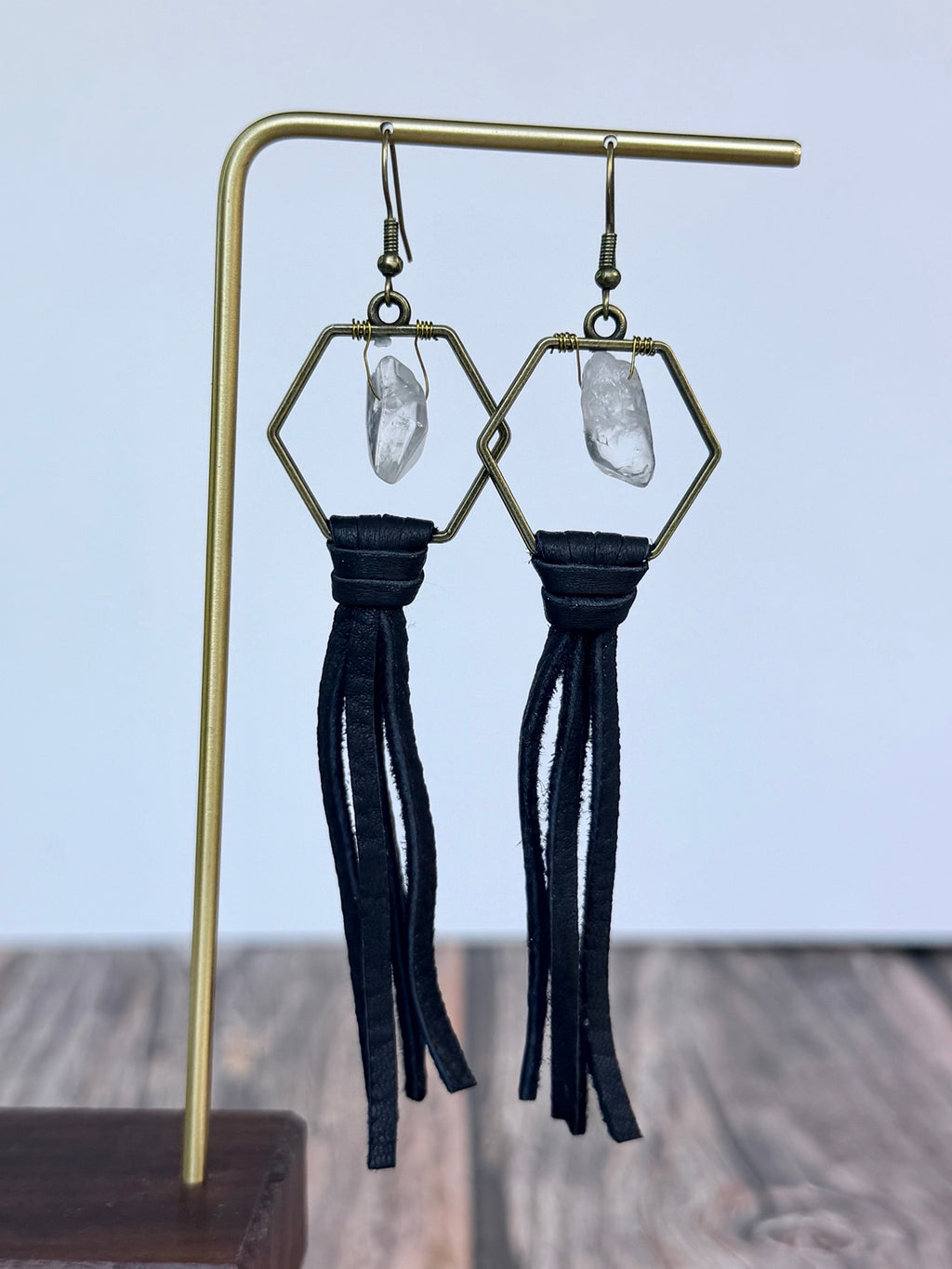 Close-up of hexagon clear quartz earrings with black leather fringe