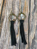 Queen Bee clear quartz and black leather tassel earrings on rustic wood