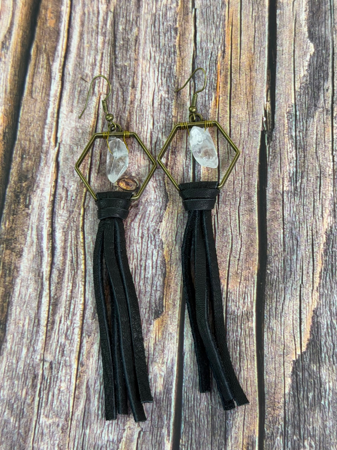 Queen Bee clear quartz and black leather tassel earrings on rustic wood