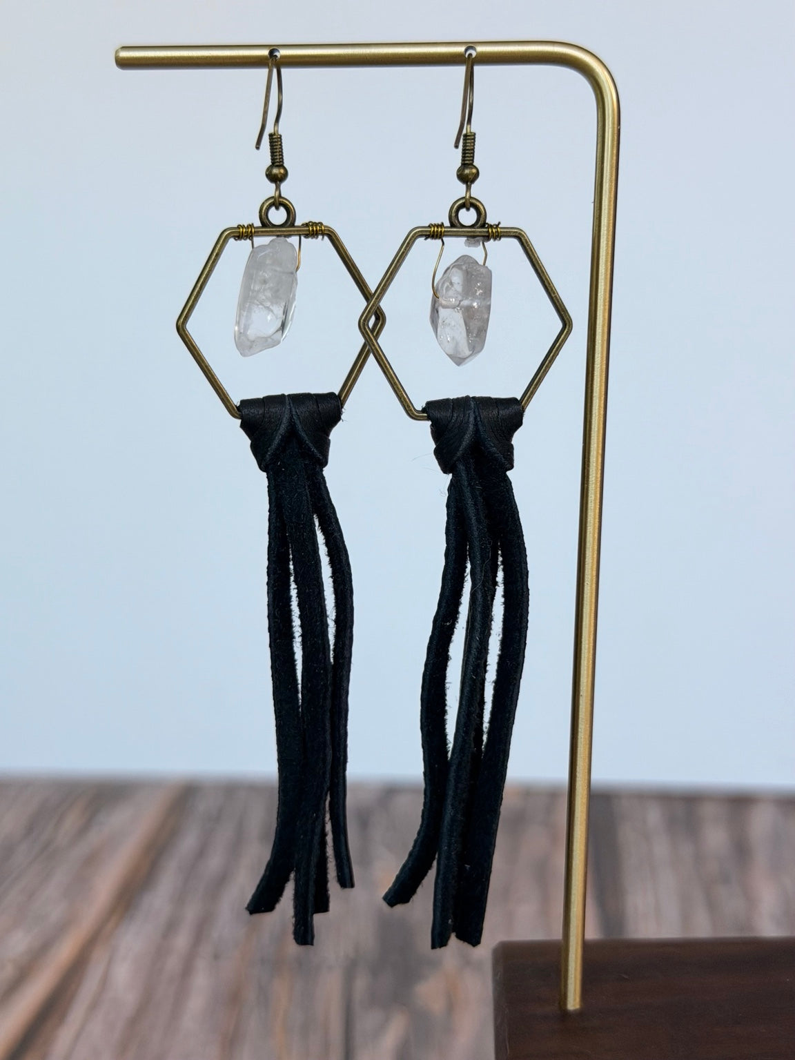 Queen Bee Clear Quartz Tassel Earrings displayed on a gold jewelry stand