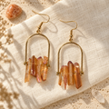 Gold-tone tangerine angel aura crystal earrings on natural linen